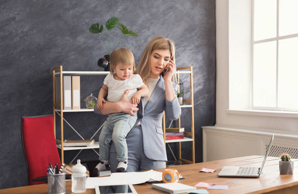 Jonge moeder bedrijf baby tijdens het gesprek op de telefoon - Foto, afbeelding