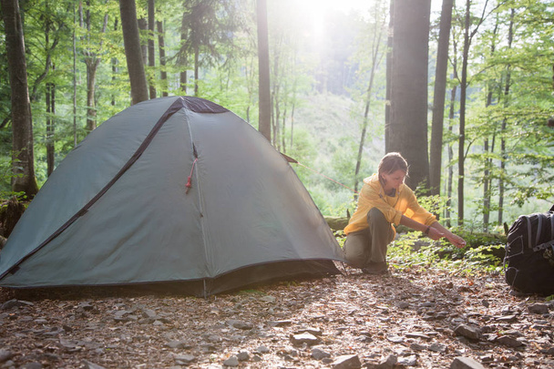 Tourism concept. Camping and hiking.  Woman setting tent in the  - Photo, Image