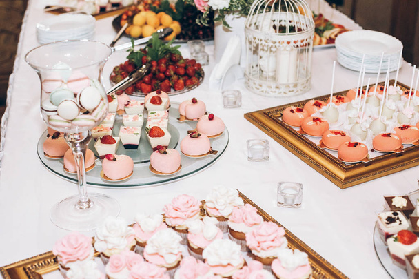 herkullisia makeisia, makeisia, cupcakes, pops koristeltu kukkia pöydällä häävastaanotossa. Suklaapa maukkaita vaaleanpunaisia makeisia juhlatilaisuuksiin ja suihkuun. ylellinen tyylikäs catering
 - Valokuva, kuva