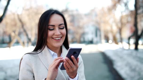 Mujer bonita usando su teléfono inteligente al aire libre
 - Metraje, vídeo