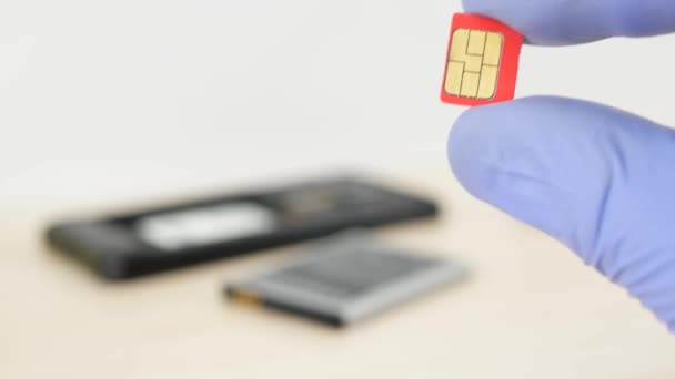 Mão segurando cartão micro-SIM vermelho no fundo do telefone móvel desmontado
 - Filmagem, Vídeo