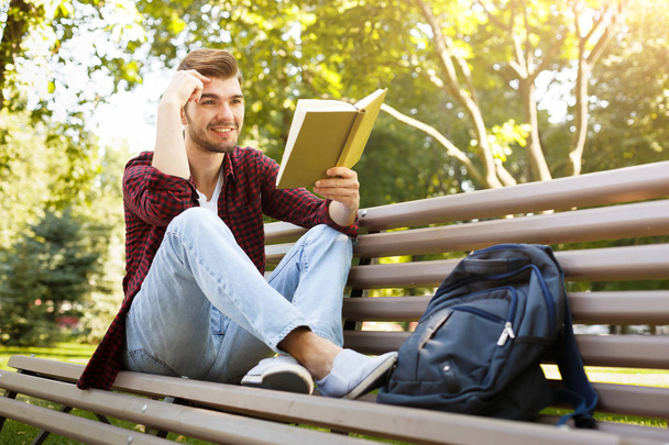 νεαρός άνδρας, διαβάζοντας ένα βιβλίο σε εξωτερικούς χώρους - Φωτογραφία, εικόνα