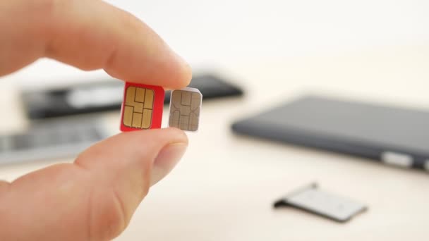 Mão segurando um micro SIM vermelho e cartões nano SIM brancos
 - Filmagem, Vídeo