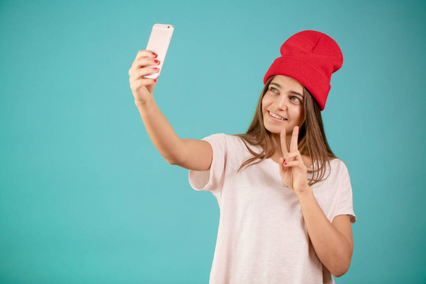 Young smiling brown-haired girl doing selfie on the isolated blue background - Foto, Imagen