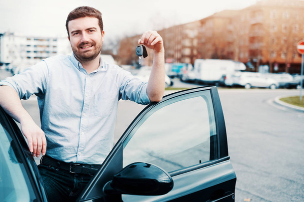 Hombre sosteniendo una llave de coche junto a su vehículo
 - Foto, Imagen