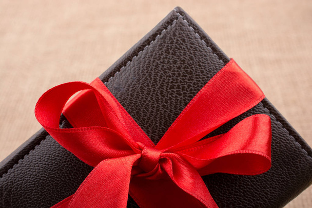 Monedero de regalo envuelto con cinta de color rojo
 - Foto, imagen