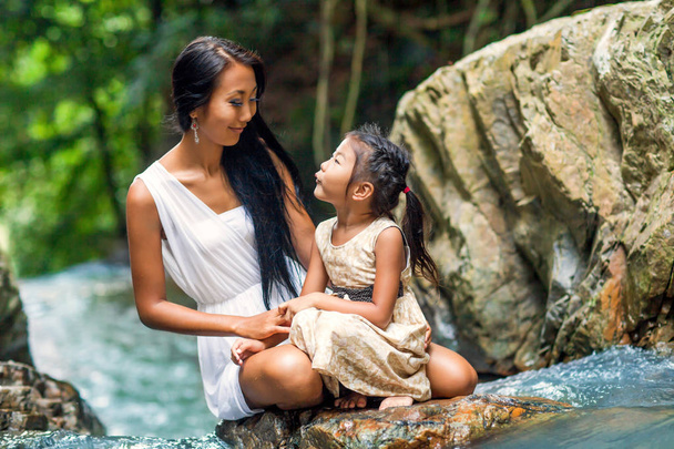 asian happy mother with her daughter in the tropics near the watterfall. Mothers day. - Fotoğraf, Görsel