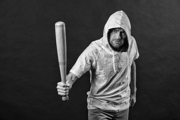 Gangster guy threaten with bat weapon. Man hold baseball bat, aggression. Hooligan wear hood in hoody, fashion. Aggression, anger and violence concept, blaack and white - Foto, Imagen