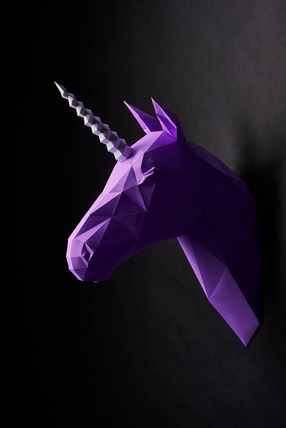 Deep shadowed violet unicorns head profile hanging on contrast wall. - Фото, изображение