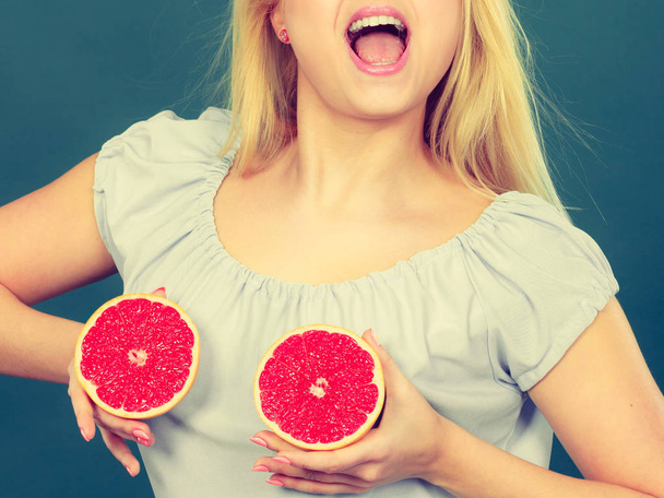 Woman holds grapefruit citrus fruit on breast - Foto, imagen