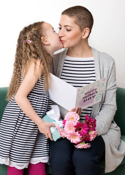 Happy Mother's Day. Cute little girl giving mom, cancer patient, greeting card, present and bouquet of pink gerbera daisies. Mother and daughter concept. - Zdjęcie, obraz
