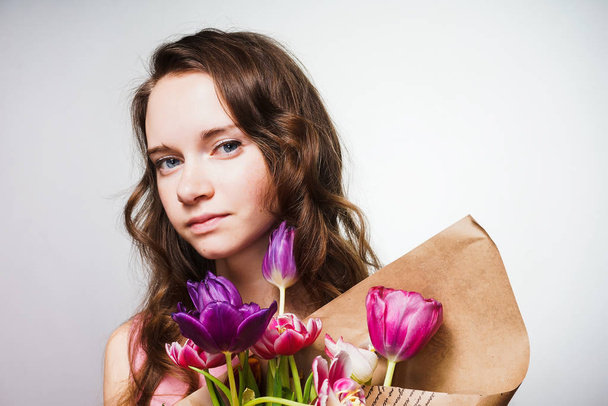 beautiful blue-eyed girl holding a big bouquet of flowers, celebrating the World Women's Day - 写真・画像