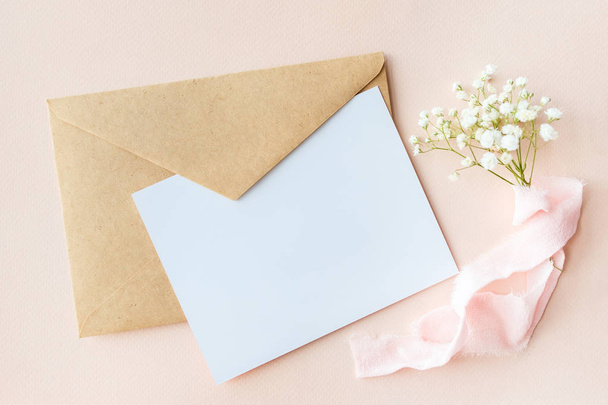 A letter on a  pink background with Gypsophila with silk ribbon, invitation for a wedding, a text card and an envelope - Fotó, kép