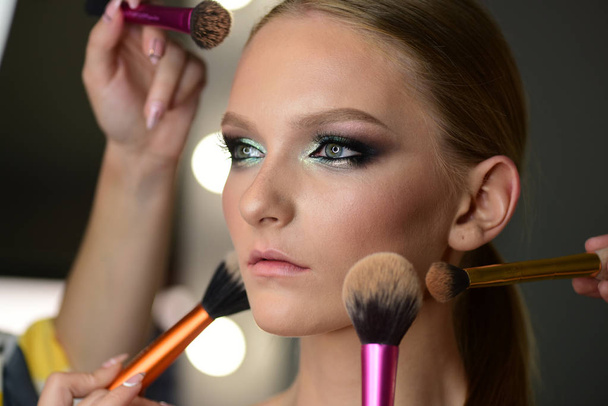 Young woman has brushes around face makeup - Foto, Imagen