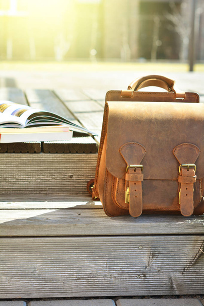 vintage natural leather backpack and books on gray rustic wooden stairs - Photo, Image