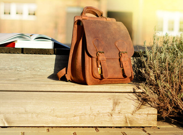 mochila de couro natural vintage e livros sobre escadas de madeira rústica cinza
 - Foto, Imagem