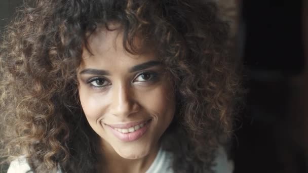headshot portrait of a attractive hispanic girl with a beautiful smile. mulatto woman smiles and looks into the camera - Filmati, video