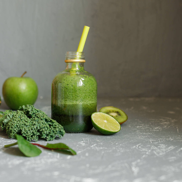 Healthy green smoothie with kale, apple, spinach, lime and kiwi on gray background - Фото, зображення