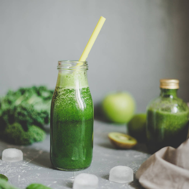 Healthy green smoothie with ingredients and ice cubes on gray background - Fotó, kép