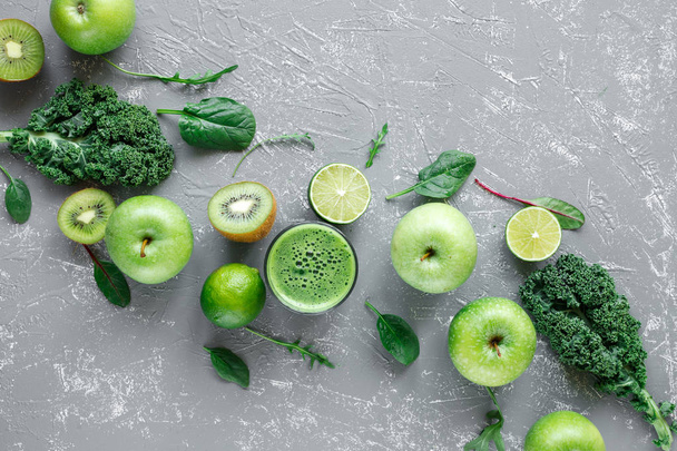 Healthy green smoothie with ripe green fruits, kale and spinach on gray background, top view - Photo, image