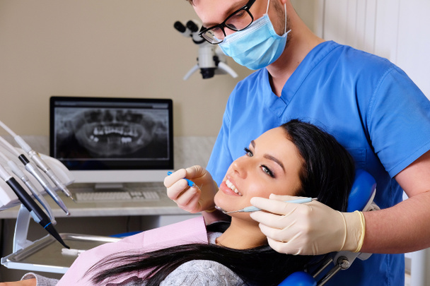 Dentista a curar uma paciente do sexo feminino. Consulta de Odontologia
 - Foto, Imagem