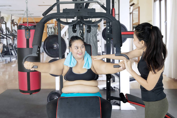 Obese woman assisted by her trainer to workout - Foto, immagini