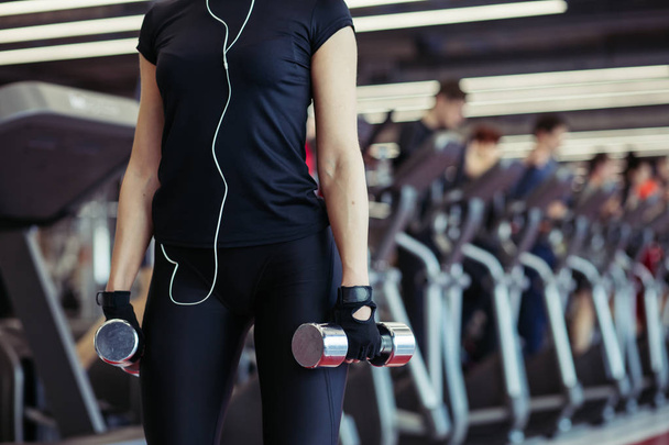 young woman posing with dumbbells in gym and looking at camera - Foto, Bild