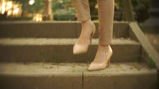thin female legs in beige trousers and high-heeled shoes stroll in the park past the puddles on the lawn. 4k, slow motion - Filmagem, Vídeo