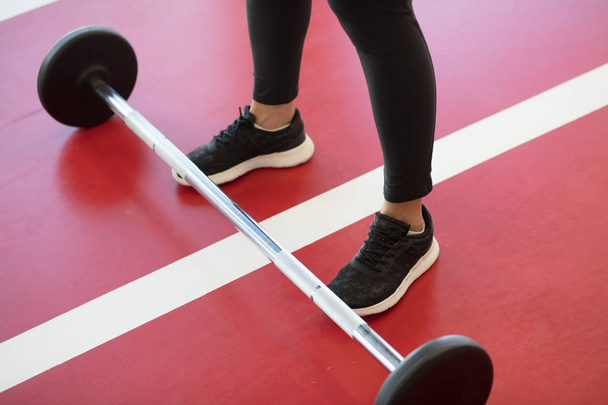 woman foots at gym with barbells on floor - Foto, afbeelding