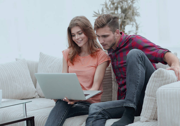 young man with his girlfriend looking at the laptop sitting on the sofa. - Fotoğraf, Görsel