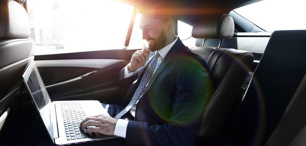 Businessman typing text on laptop while sitting in car - Fotó, kép