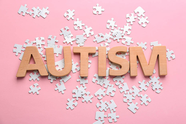 Word "Autism" and puzzle pieces on color background - Foto, Imagem