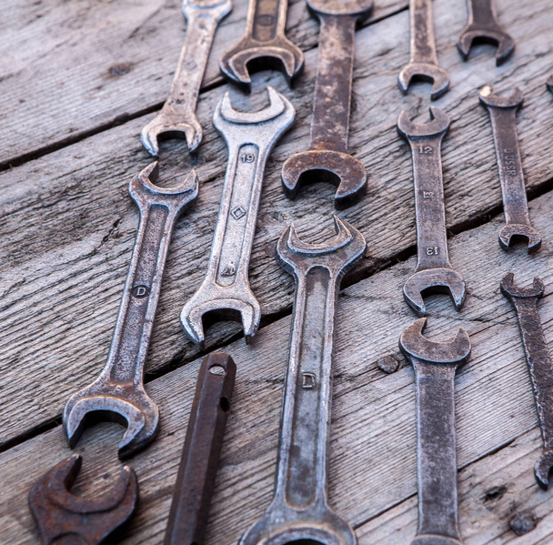 Metal wrench rusty tools lying on a black wooden table. Hammer, chisel, hacksaw, metal wrench - 写真・画像