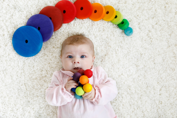 Roztomilá holčička hrát s hračkami, barevné dřevěné chrastítko - Fotografie, Obrázek