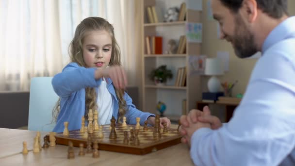 Little blond girl playing chess with her father at home, hobby and relaxation - Кадри, відео