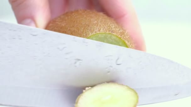 Kiwi being sliced in half on wet white background. Close up - Séquence, vidéo