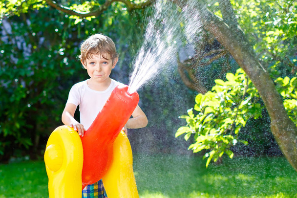 niño jugando con un aspersor de agua de manguera de jardín
 - Foto, Imagen