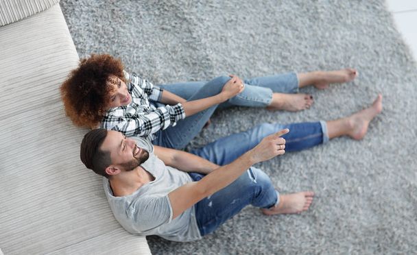 newlywed couple sitting on a carpet in a new living room - Foto, Imagen