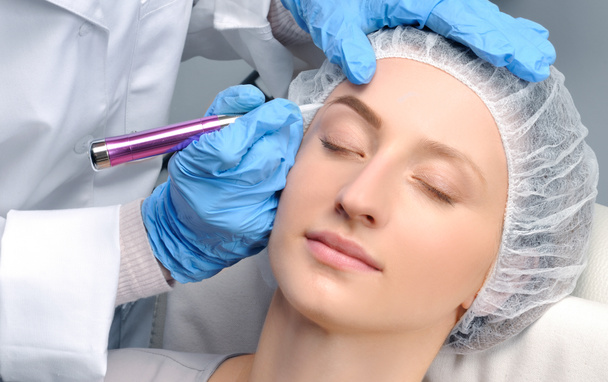 Microblading. Cosmetologist making permanent makeup. Attractive woman getting facial care and tattoo eyebrows - 写真・画像