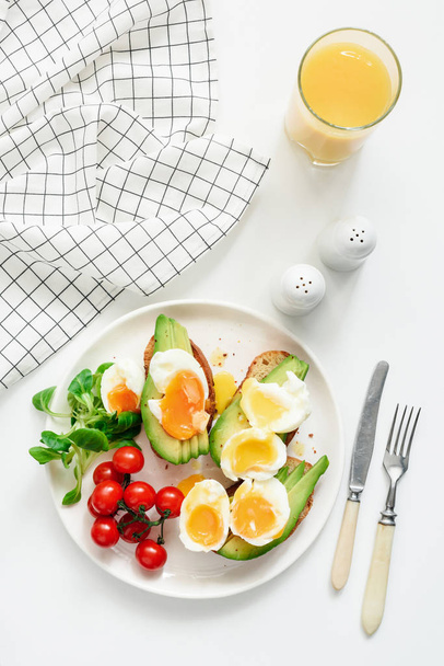 Healthy avocado and egg toasts and orange juice for breakfast on white background - Zdjęcie, obraz