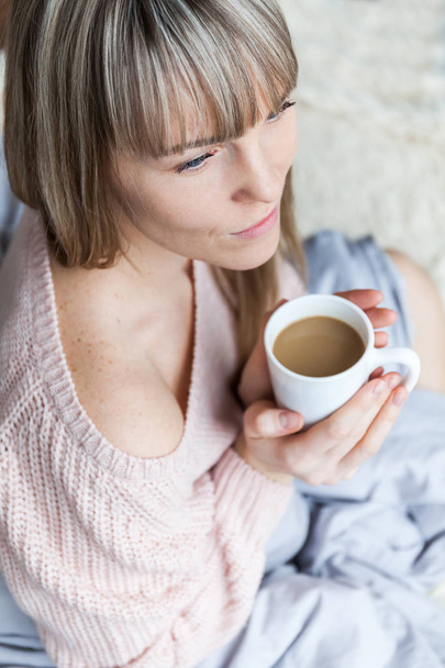 Retrato de Beleza Mulher Relaxada pela Manhã e Bebe Café na Cama. Mulher branca Relaxado na cama com xícara de café
 - Foto, Imagem