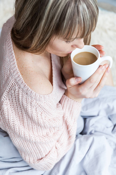 Beauty Portrait Relaxed Woman in the Morning and Drinks Coffee in Bed. Caucasian young woman Relaxed in Bed with cup of coffee - Foto, imagen