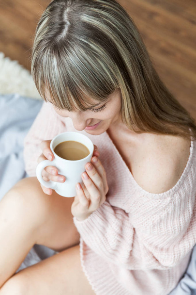 Beauty Portrait Relaxed Woman in the Morning and Drinks Coffee in Bed. Caucasian young woman Relaxed in Bed with cup of coffee - Foto, imagen