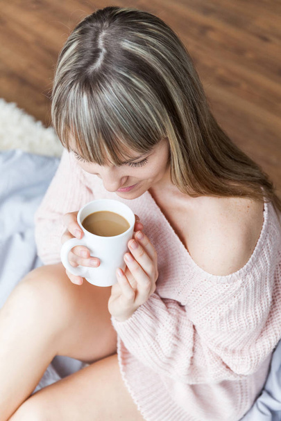 Beauty Portrait Relaxed Woman in the Morning and Drinks Coffee in Bed. Caucasian young woman Relaxed in Bed with cup of coffee - Photo, Image