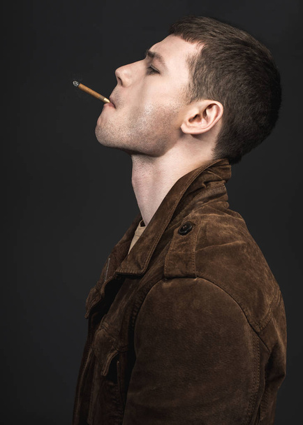 Thoughtful young man lighting cigar - Fotó, kép