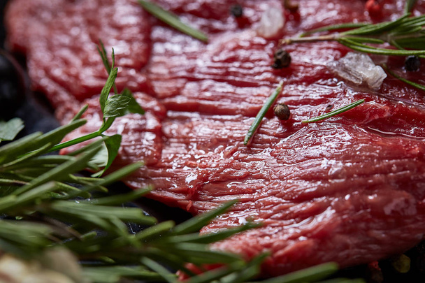 Flat lay of raw beefsteak with vegetables, herbs and spicies on metal tray, close-up, selective focus - Foto, imagen