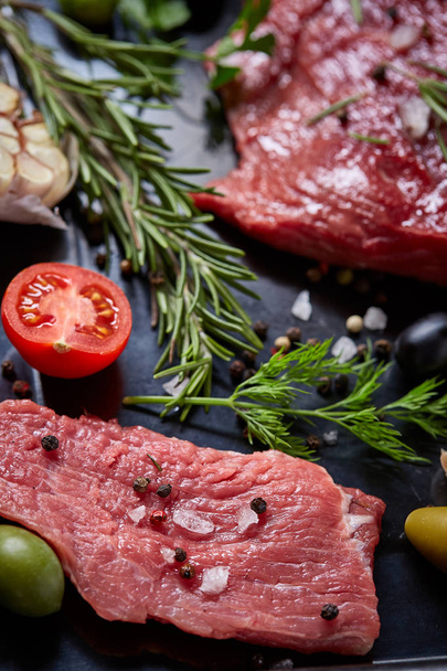 Flat lay of raw beefsteak with vegetables, herbs and spicies on metal tray, close-up, selective focus - Foto, imagen