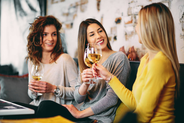 Vriendinnen wijn drinken en chatten tijdens de vergadering in de bar. - Foto, afbeelding