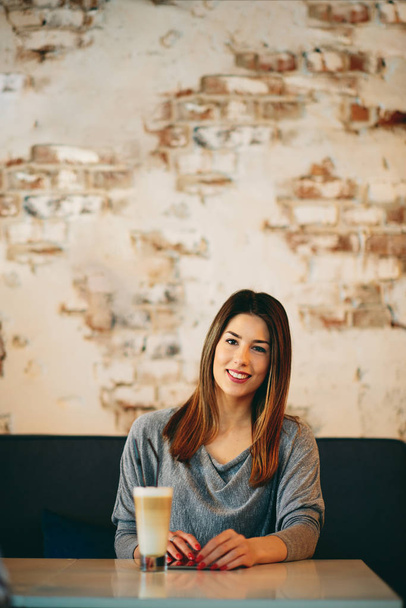 Młoda kobieta kaukaski za pomocą tabletu siedząc w kawiarni i picia kawy. - Zdjęcie, obraz