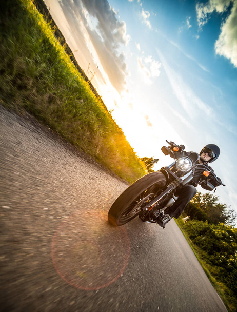 Mies ratsastus urheilu moottoripyörä auringonlaskun aikana
. - Valokuva, kuva